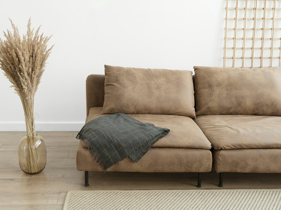 Tan leather sofa with a grey throw in a bright, minimal room