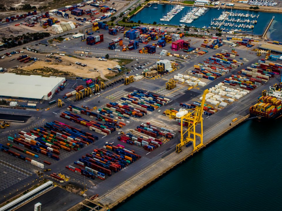 Aerial view of a container port with cranes and a cargo ship