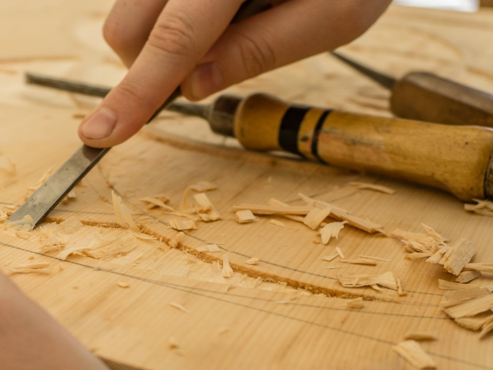 Hand carving a wooden panel with a chisel